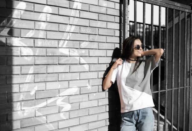 dívka opřená o zeď v bílo-šedém tričku Sledgehammer