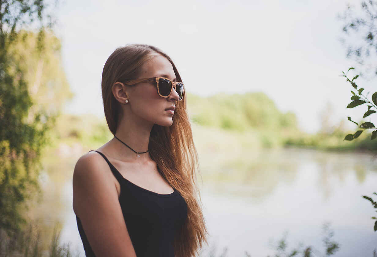 pózující modelka u jezera v dřevěných slunečních brýlích