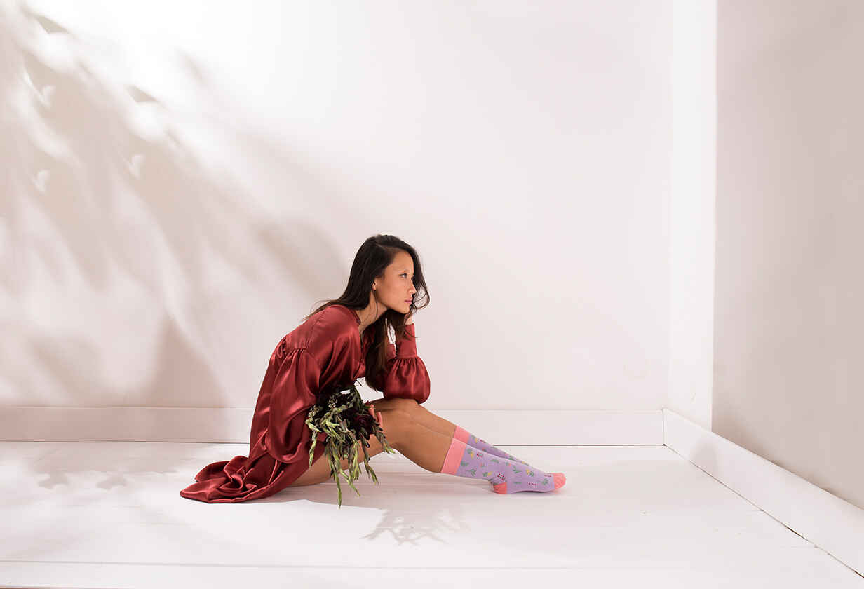modelka sedící na podlaze v saténových šatech a barevných ponožkách