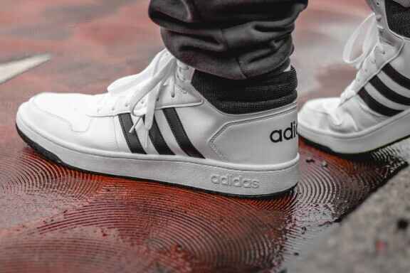 bílé boty adidas na mokrém povrchu