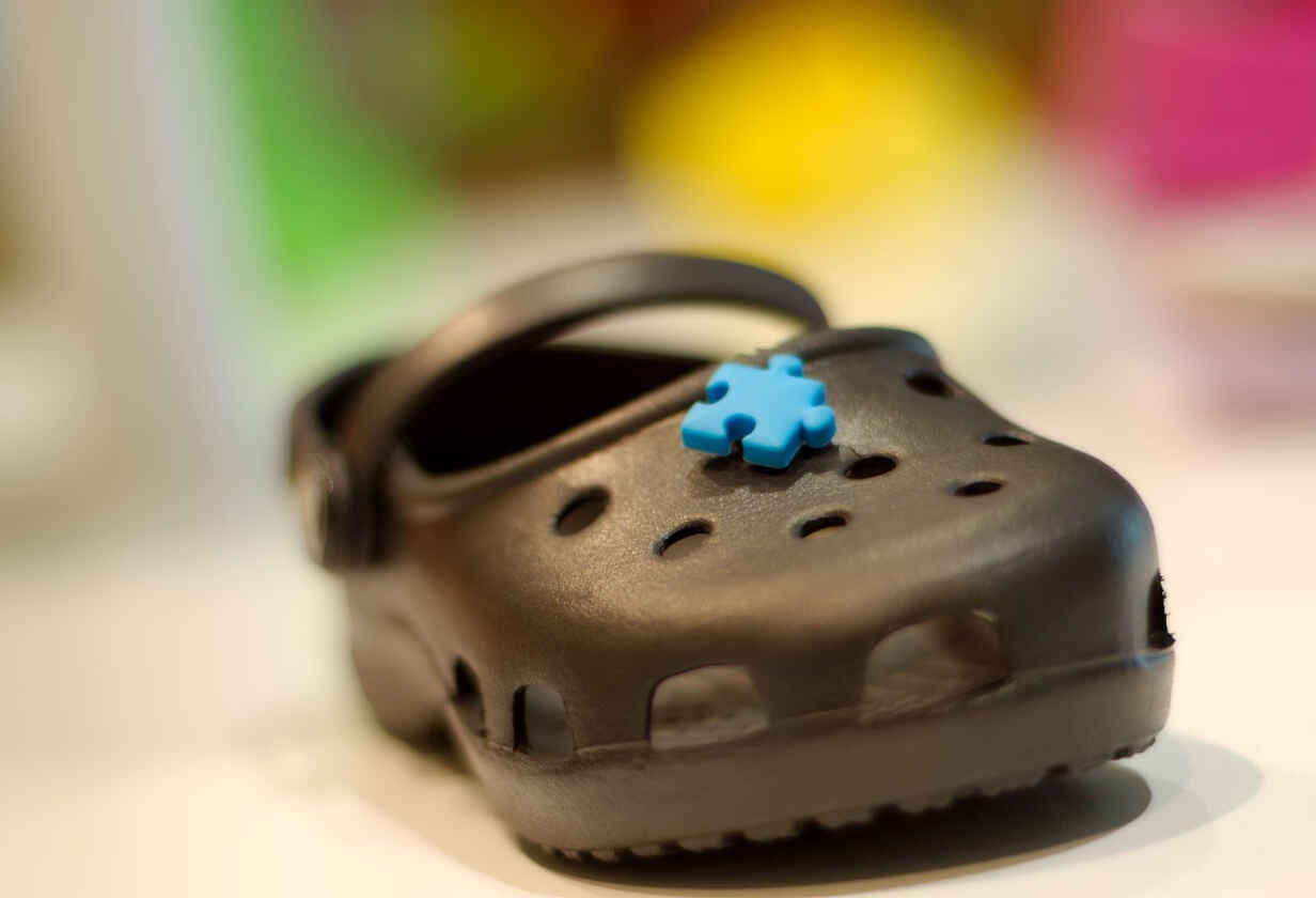záběr na černé boty crocs s modrým dílkem puzzle na vrchu