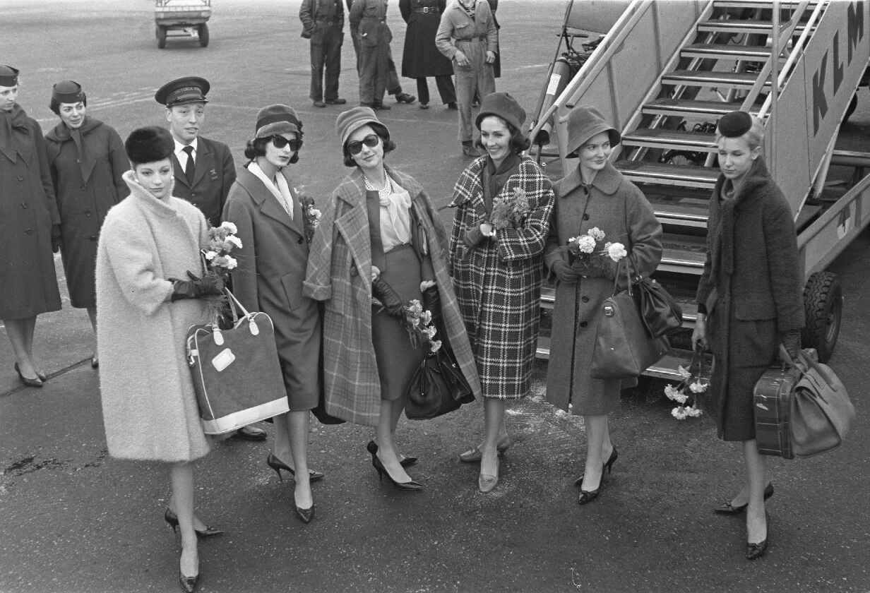 šest žen stojících na letištní ploše před schody do letadla