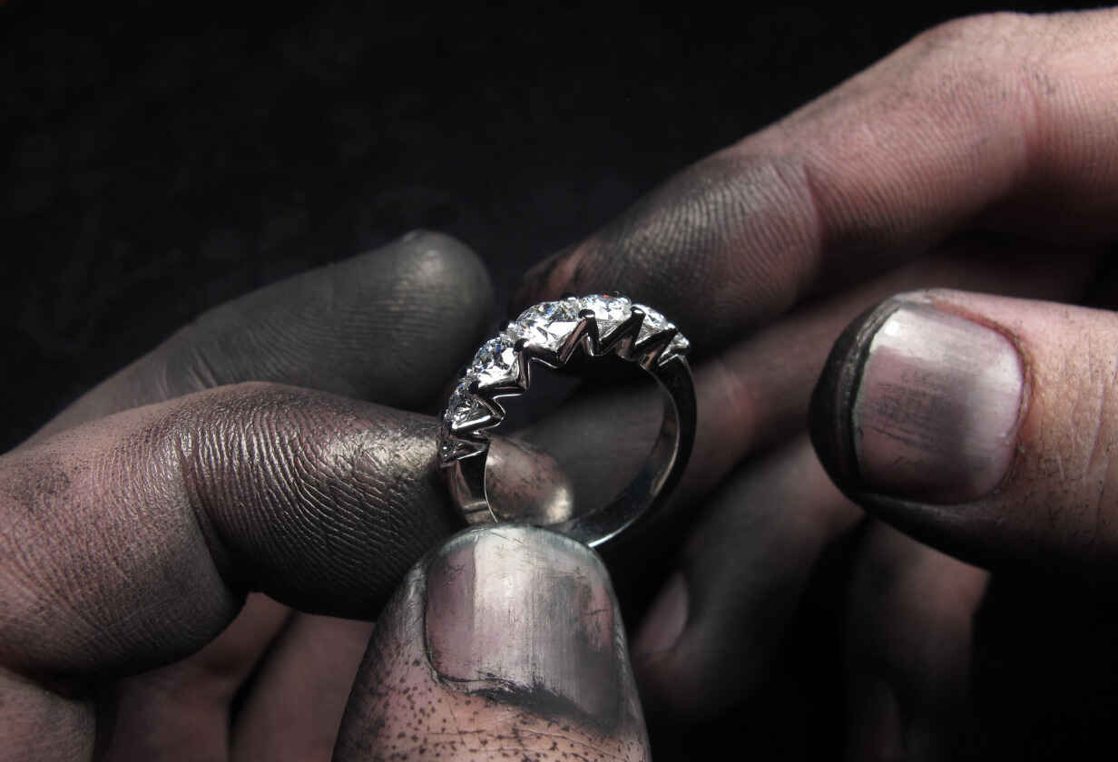 ruce držící stříbrný prsten s diamanty