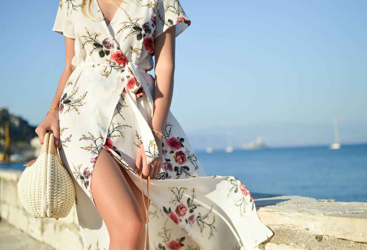 Žena v letních šatech jde po pláži