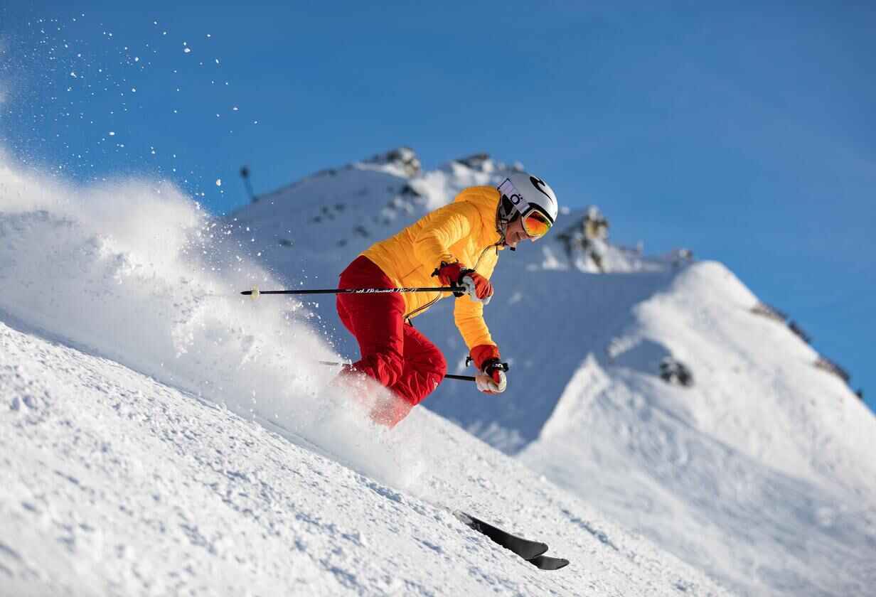 lyžař v lyžařské bundě a kalhotách sjíždí svah