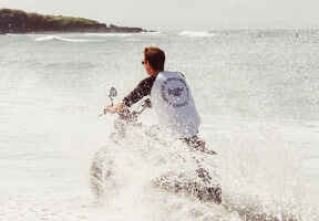 muž na motorce projíždějící mořem