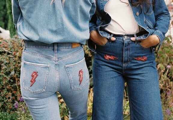 dvě ženy v džínách s výšivkou na kapsách