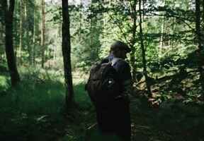 muž v lese s batohem na zádech