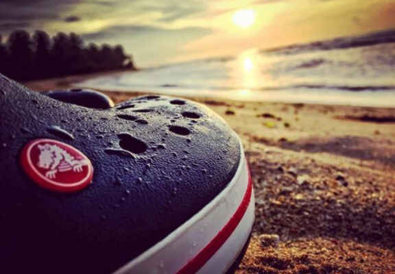 boty crocs s mořem a západem slunce v popředí