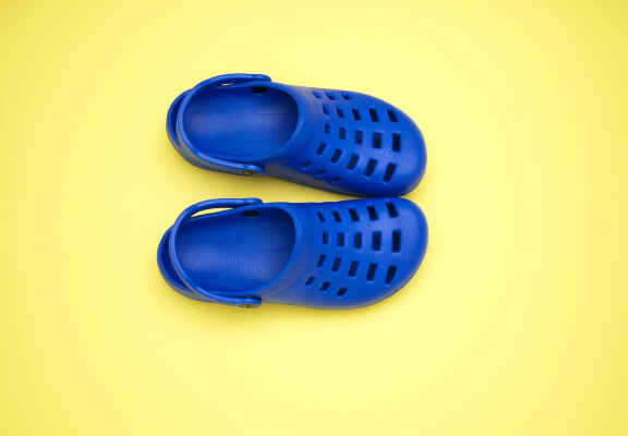 modré pantofle crocs na žlutém pozadí