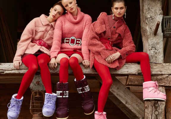 tři sedící ženy v růžovo-červeném oblečení a sněhulemi moon boot