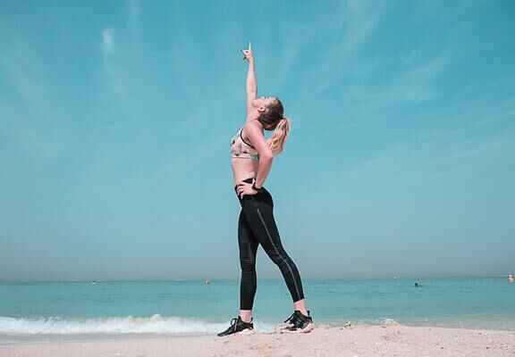 Stojící žena na pláži u moře ve sportovním oblečení