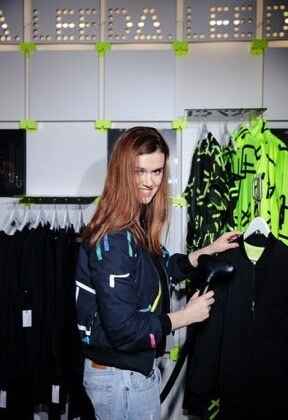 usmívající se návrhářka napařuje bundu ve svém butiku